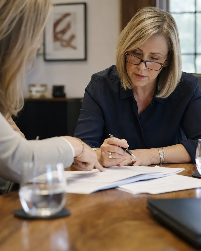 A COO reads a printed engagement proposal at a conference table, pen in hand, while a colleague points at a line on the page